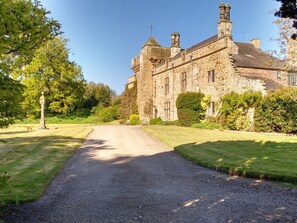 A historic stone building with a gravel driveway leading to a well-maintained lawn. - Tower (Mold)