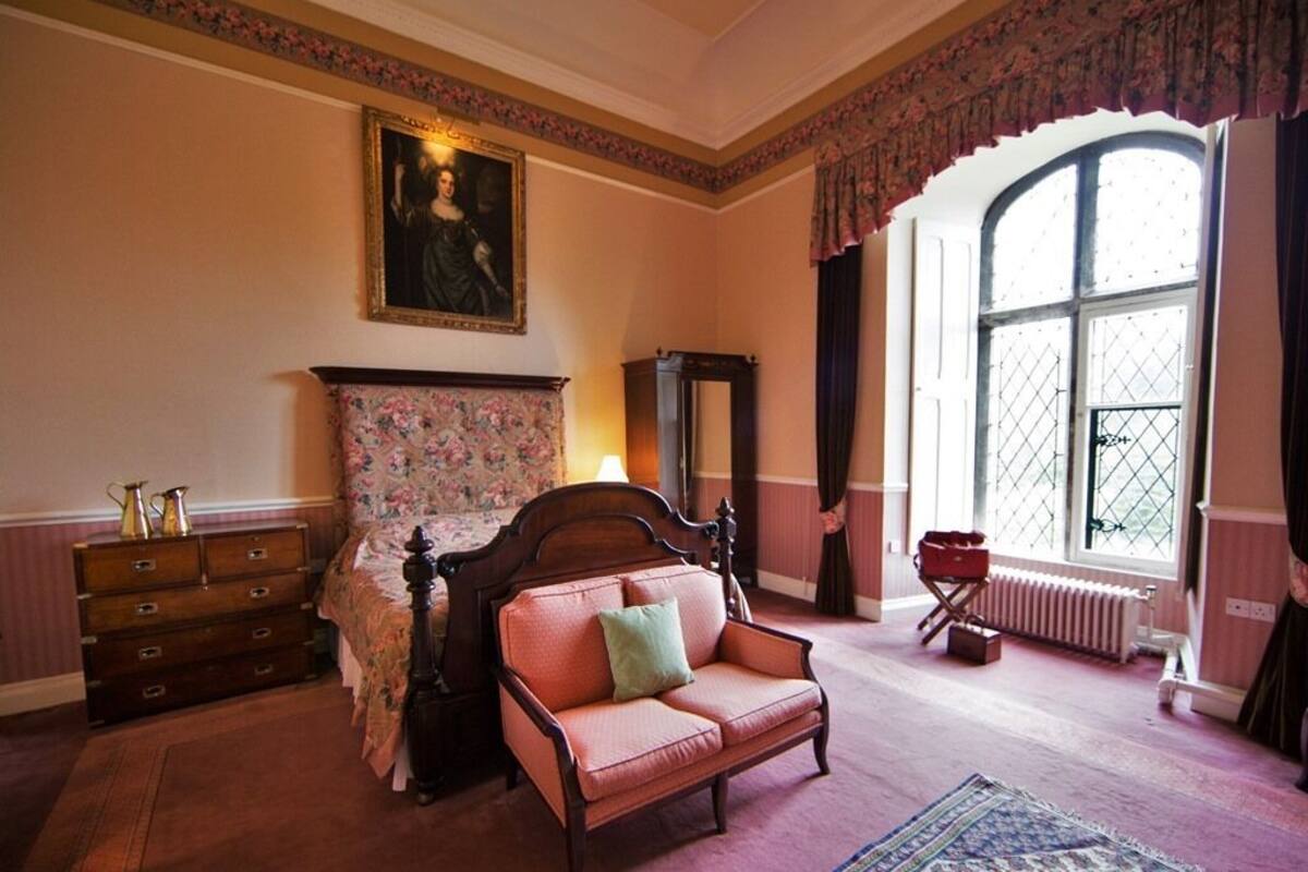 Une chambre avec un lit, un canapé, une commode, un miroir et une fenêtre donnant sur un beau paysage.