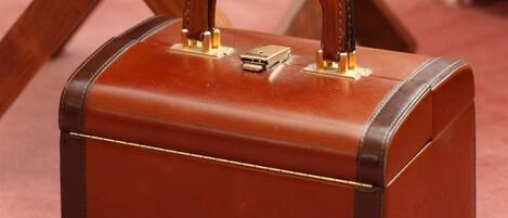 A brown suitcase with a handle and a lock, placed on a wooden chair.