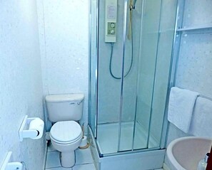 A small, compact bathroom with a glass-enclosed shower, a toilet, and a sink. - The Argyll Hotel (Ullapool)