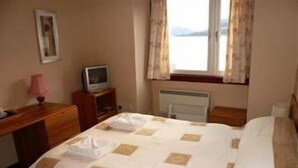 Ein Hotelzimmer mit Bett, Schreibtisch, Fernseher und einem Fenster mit Vorhängen.