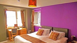 A bedroom with a large bed, a desk, and a window with curtains. - The Argyll Hotel (Ullapool)