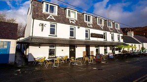 A two-story building with the sign "Argyll Hotel" on the front. There are outdoor tables and chairs in front of the building. - The Argyll Hotel (Ullapool)