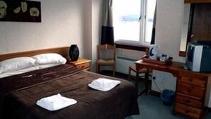 Ein Hotelzimmer mit Bett, Schreibtisch, Stuhl, Fernseher und Fenster.
