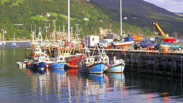 A harbor with boats docked, a crane, and a mountainous backdrop. - The Argyll Hotel (Ullapool)