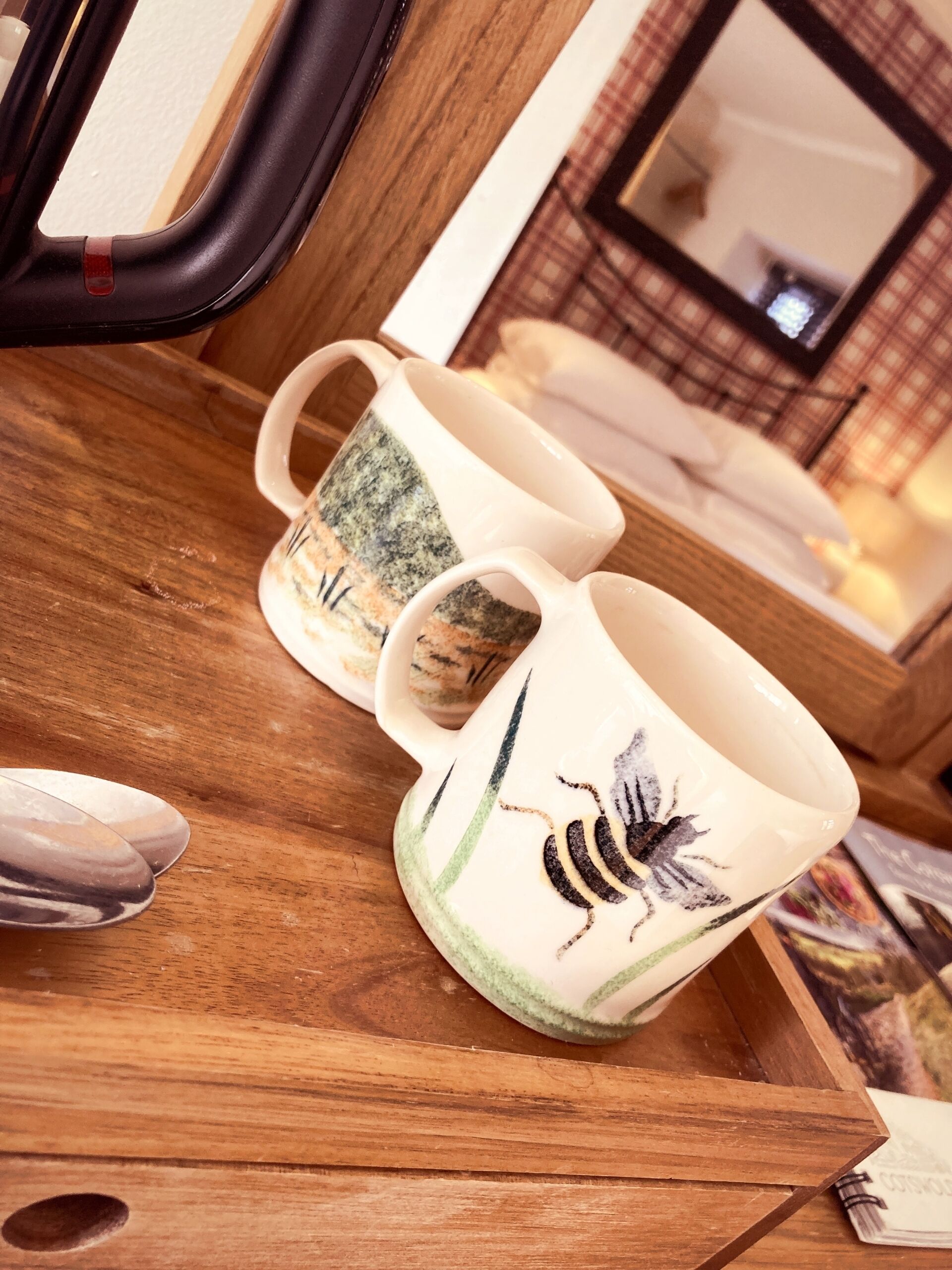 A tray with two ceramic mugs featuring a bee design, placed on a wooden surface.