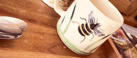 A tray with two ceramic mugs featuring a bee design, placed on a wooden surface.