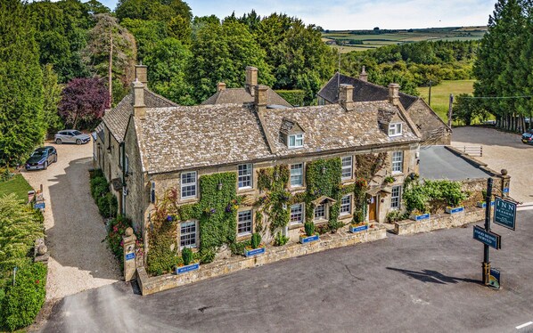 A stone building with multiple windows, a garden, and signs indicating a hotel, restaurant, and beer garden.