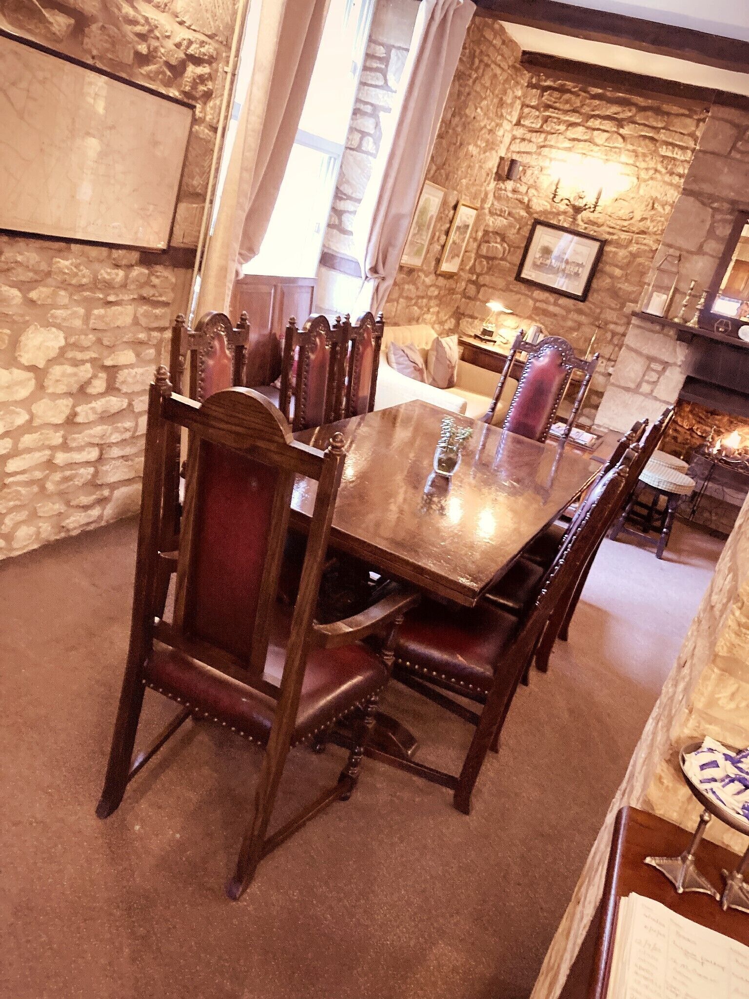 A dining area with a stone wall, wooden table, and upholstered chairs.