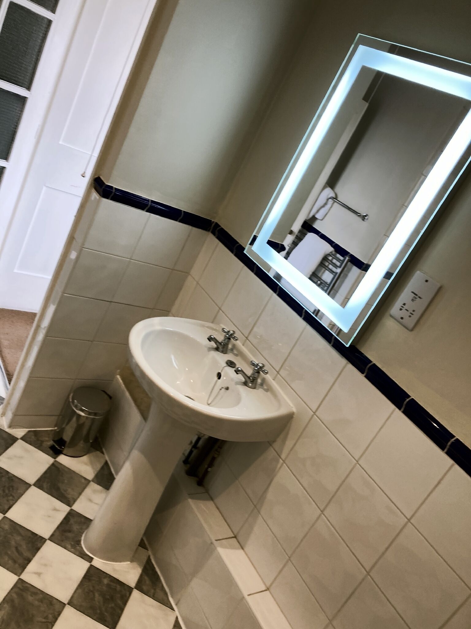 A bathroom with a white sink, a mirror, and a trash can.