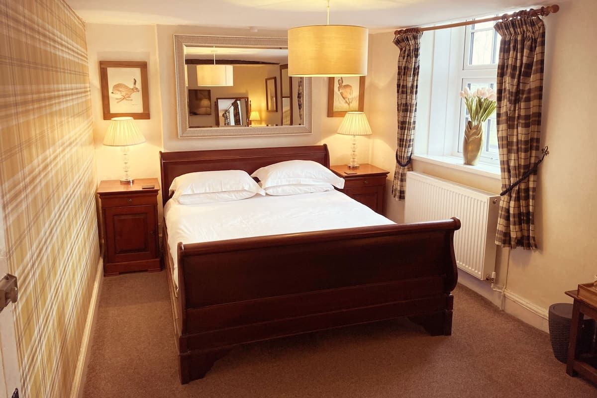 A neatly made bed with white linens, a wooden headboard, and two bedside lamps.