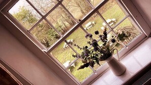 A window with a view of a garden and a white bench. - Inn For All Seasons (Burford)