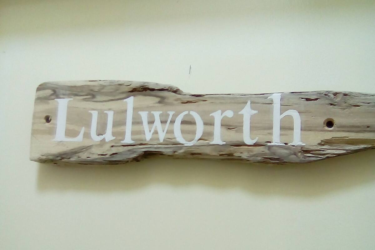 A wooden sign with the name "Lulworth" mounted on a wall.