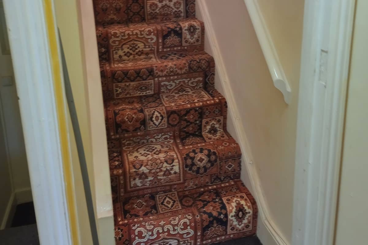 A staircase with patterned carpet.