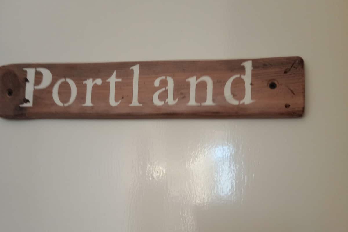 A wooden sign with the word "Portland" mounted on a wall.