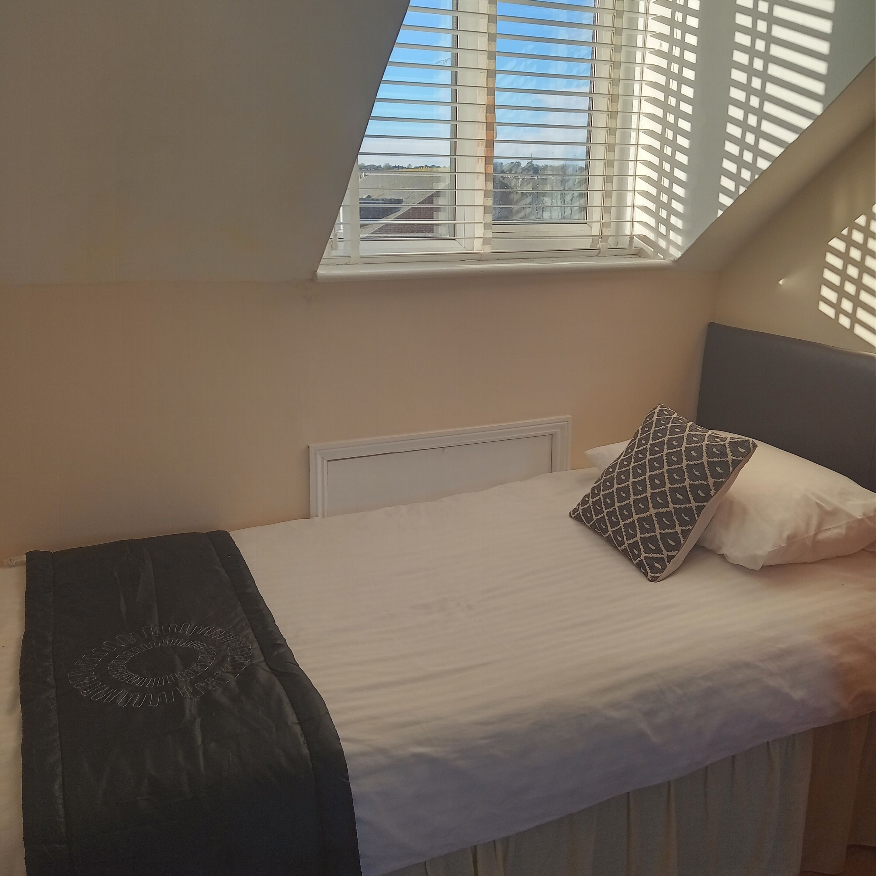 Une petite chambre avec un lit simple, un plafond en pente et un puits de lumière.