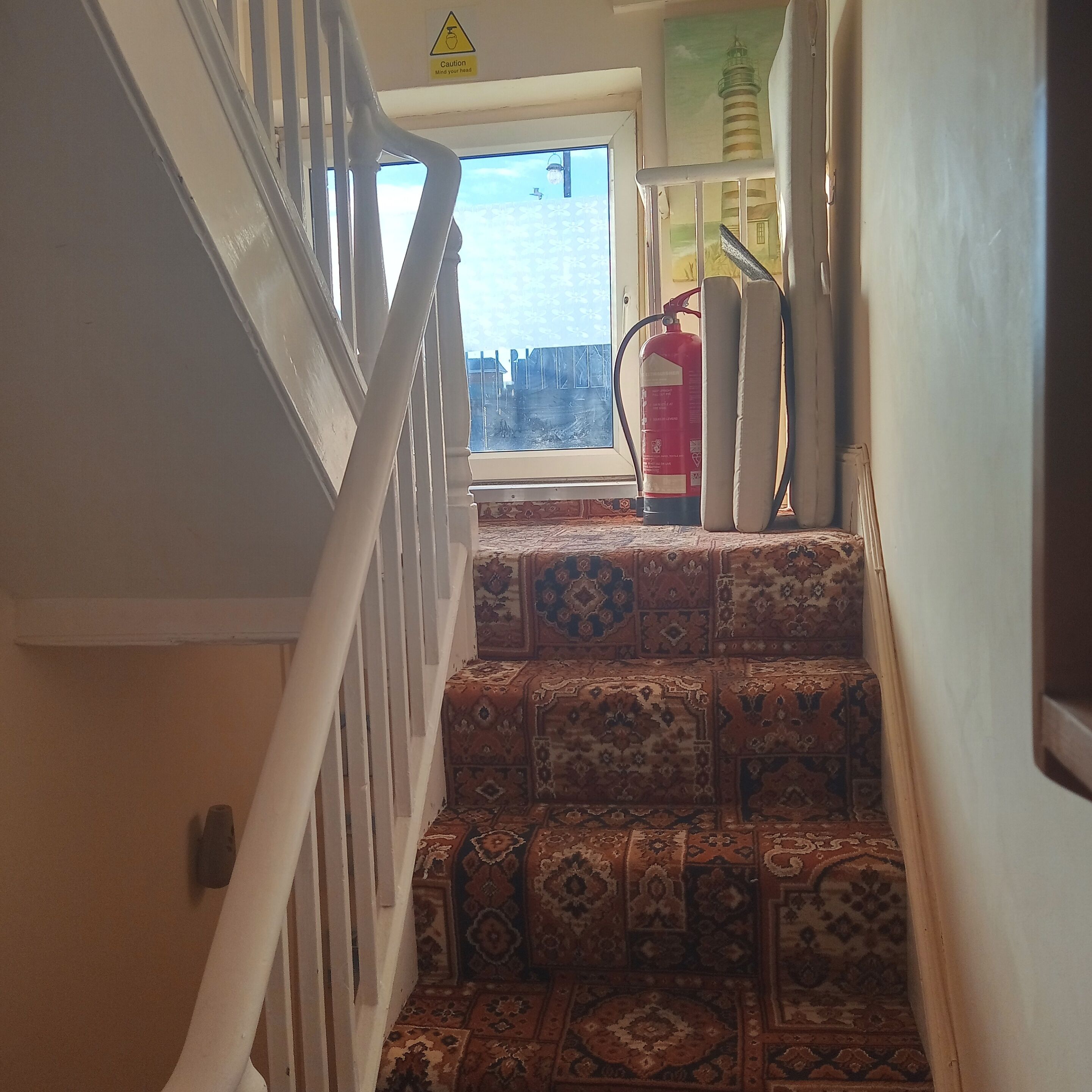 A staircase with patterned carpet leading to a window overlooking a cityscape.