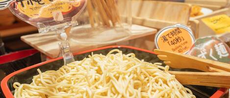 Un tazón de fideos instantáneos con un borde rojo y una cuchara de madera encima.