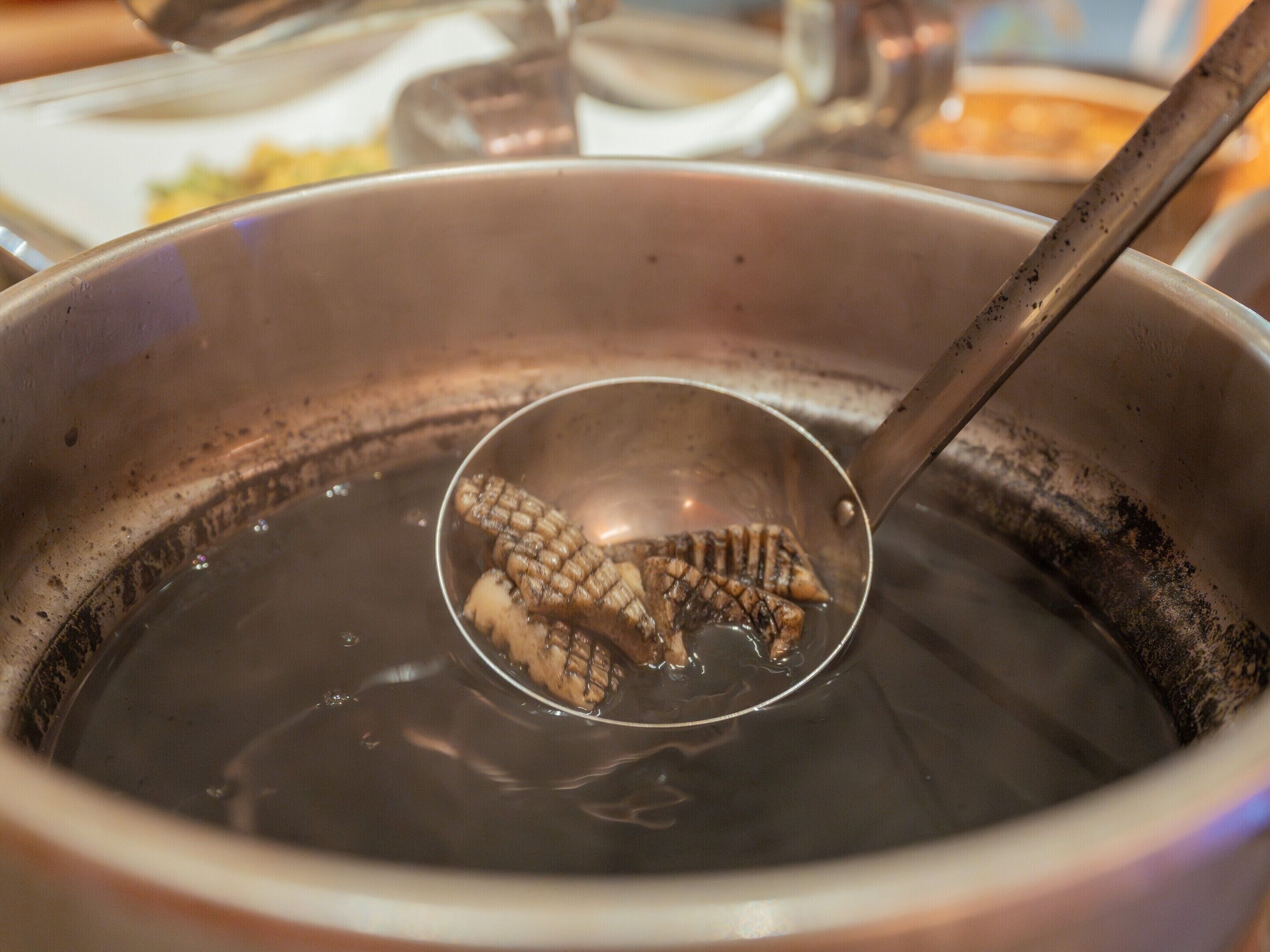 A close-up of a pot with a ladle containing food items.