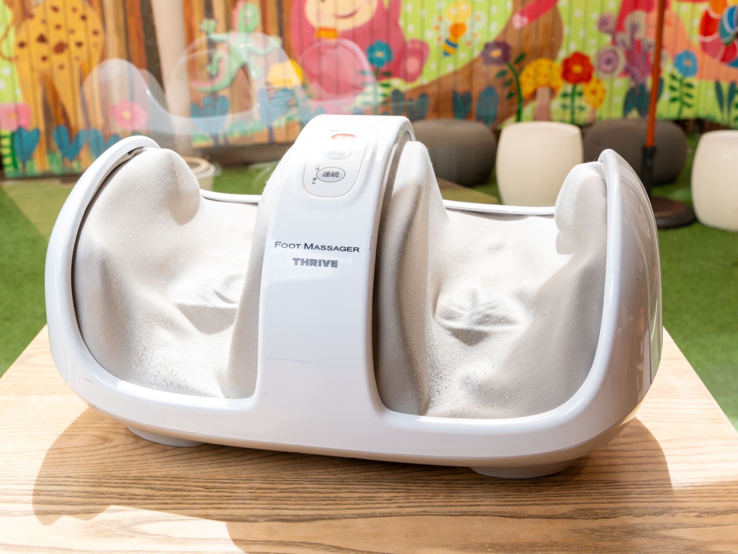 Un masajeador de pies con la etiqueta 'Foot Massager THRIVE' sobre una mesa de madera.
