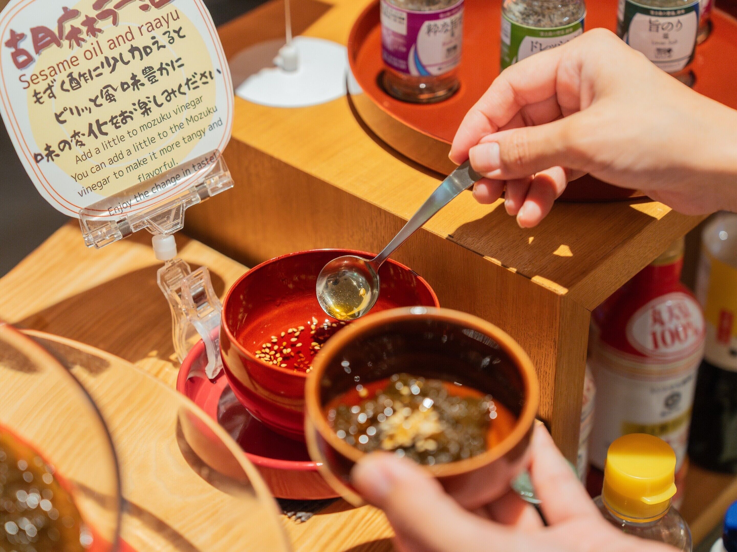 A person pouring a liquid from a bottle into a bowl.