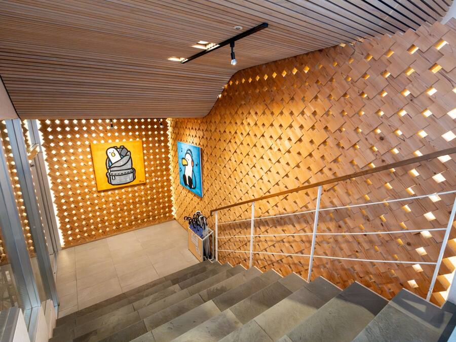 Una escalera con un muro de madera que presenta patrones geométricos y dos obras de arte enmarcadas.