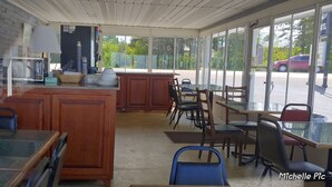A restaurant with a wooden counter, tables, and chairs. - Northwinds Motel (Mackinaw City)