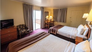 A hotel room with two beds, a television, a desk, and a chair. - Northwinds Motel (Mackinaw City)