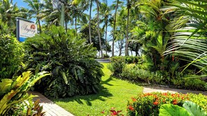 Un exuberante jardín con palmeras, un sendero pavimentado y un letrero del hotel 'Argosy on the beach'.