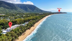 Zona costera con playa, un complejo turístico con varias edificaciones y una montaña al fondo.