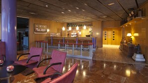 A lobby with a reception desk, bar area, and seating with chairs and a table.