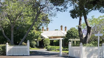 A traditional house with a prominent chimney, surrounded by lush greenery and a white picket fence.