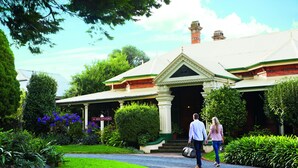 A large, traditional house with a well-maintained garden and a gravel driveway.