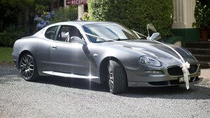 A silver sports car parked on a driveway with a reception sign in the background.