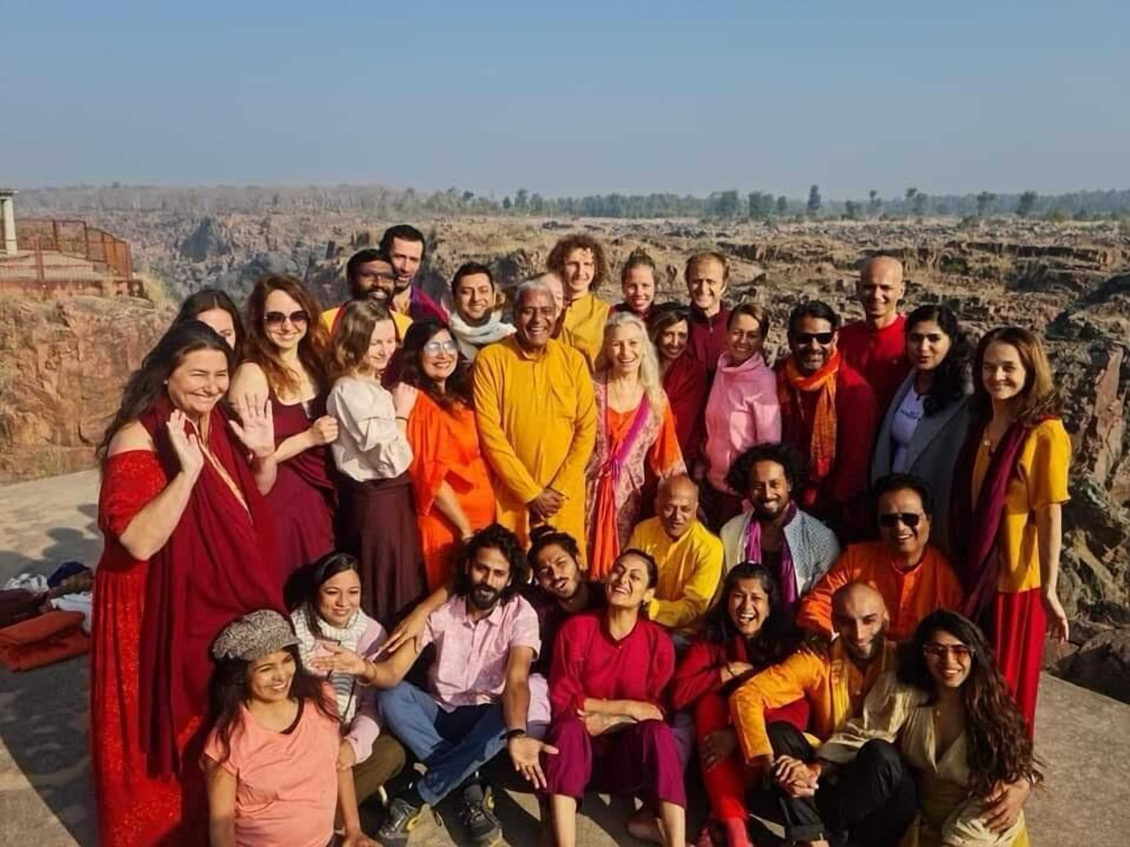 Un grupo de personas reunidas al aire libre, posiblemente en un sitio histórico con terreno rocoso al fondo.