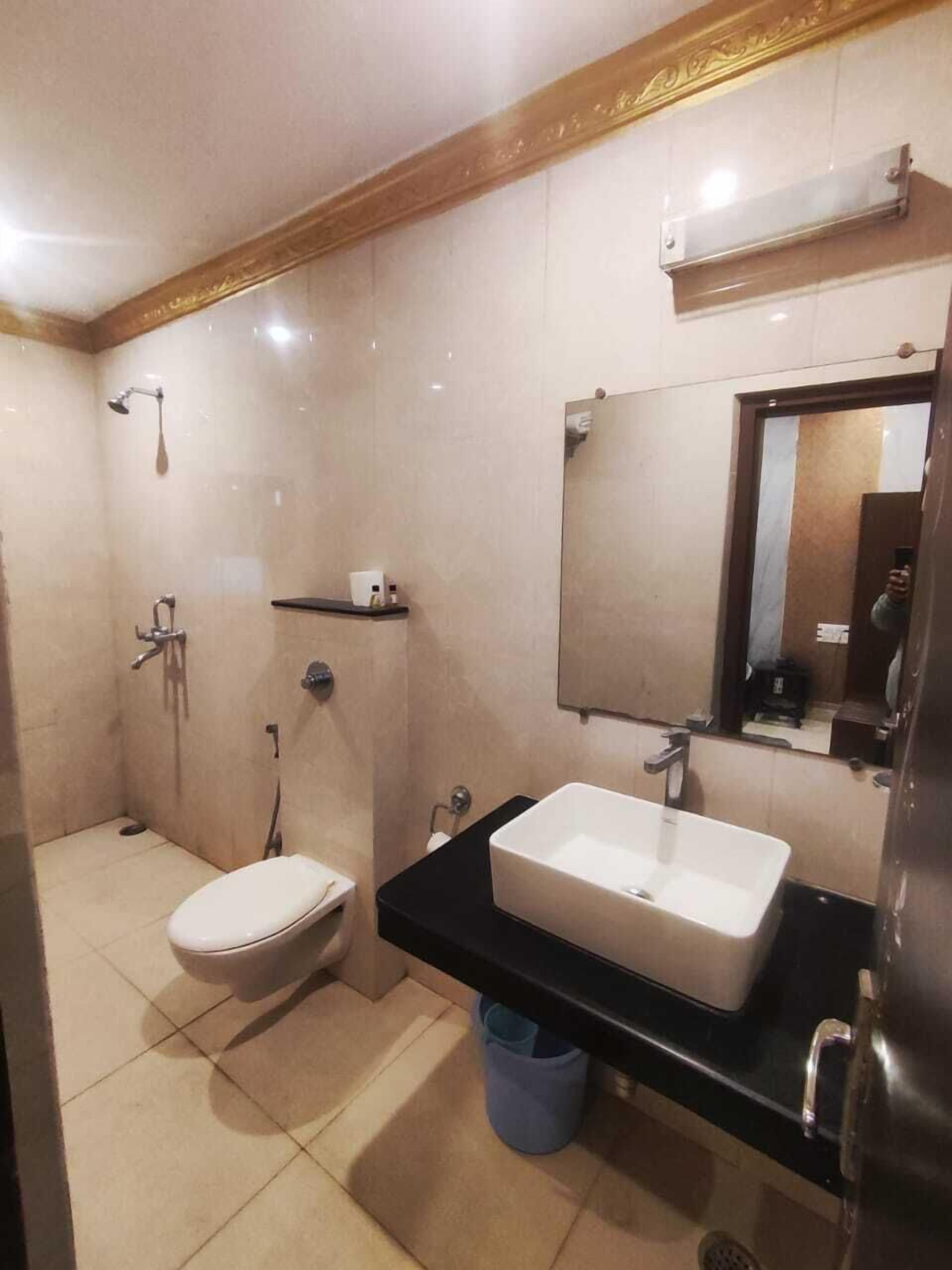 A modern bathroom with a toilet, a shower, a sink, and a mirror.