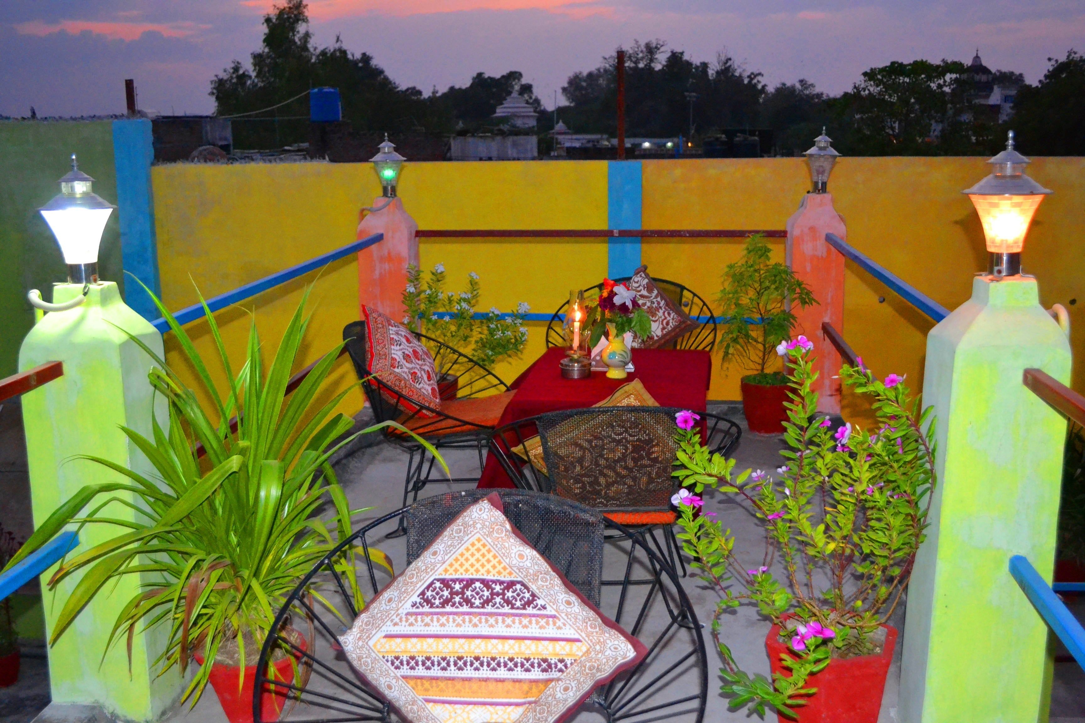 An outdoor seating area with chairs and tables, potted plants, and decorative lanterns.