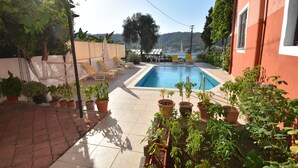 A pool area with a tiled floor, potted plants, and lounge chairs. - Duygu Pension (Fethiye)
