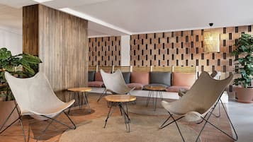 Un área de lounge moderna con asientos acolchados, detalles de madera y un revestimiento de pared estampado.