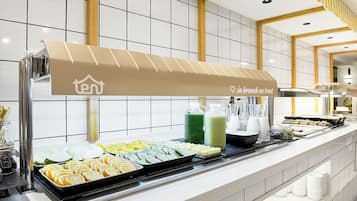 Ein reichhaltiges Buffet mit verschiedenen Speisen und Getränken, ein Beschilderungselement mit Firmenlogo und ein sauberer, gefliester Hintergrund.