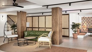 A modern interior with a green sofa, white and wicker chairs, a wooden accent wall, and a ceiling fan. - tent Capi Playa (Palma de Mallorca)