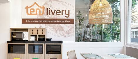 Un área de cocina moderna con microondas, lavamanos y un mueble de madera con contenedores de reciclaje etiquetados como “Envases Plástico”, “Vidrio” y “Orgánico”.
