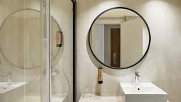 Een moderne badkamer met een douchecabine van glas, een ronde spiegel en een wit wastafelmeubel.
