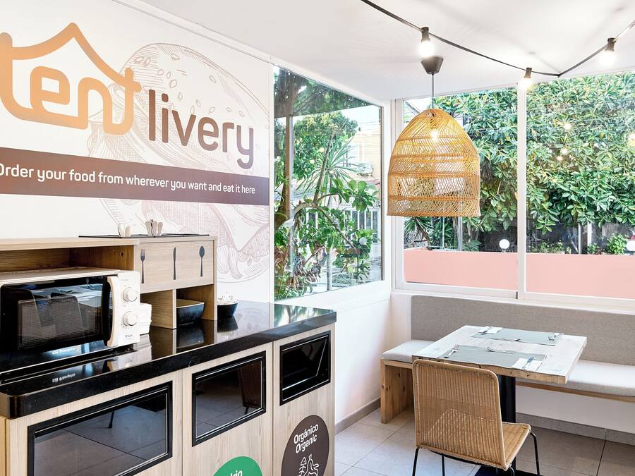 A modern kitchen area with a microwave, cabinets, and a seating area with a table and chairs.