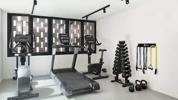 A home gym with treadmills, an elliptical, a stationary bike, kettlebells, and resistance bands.