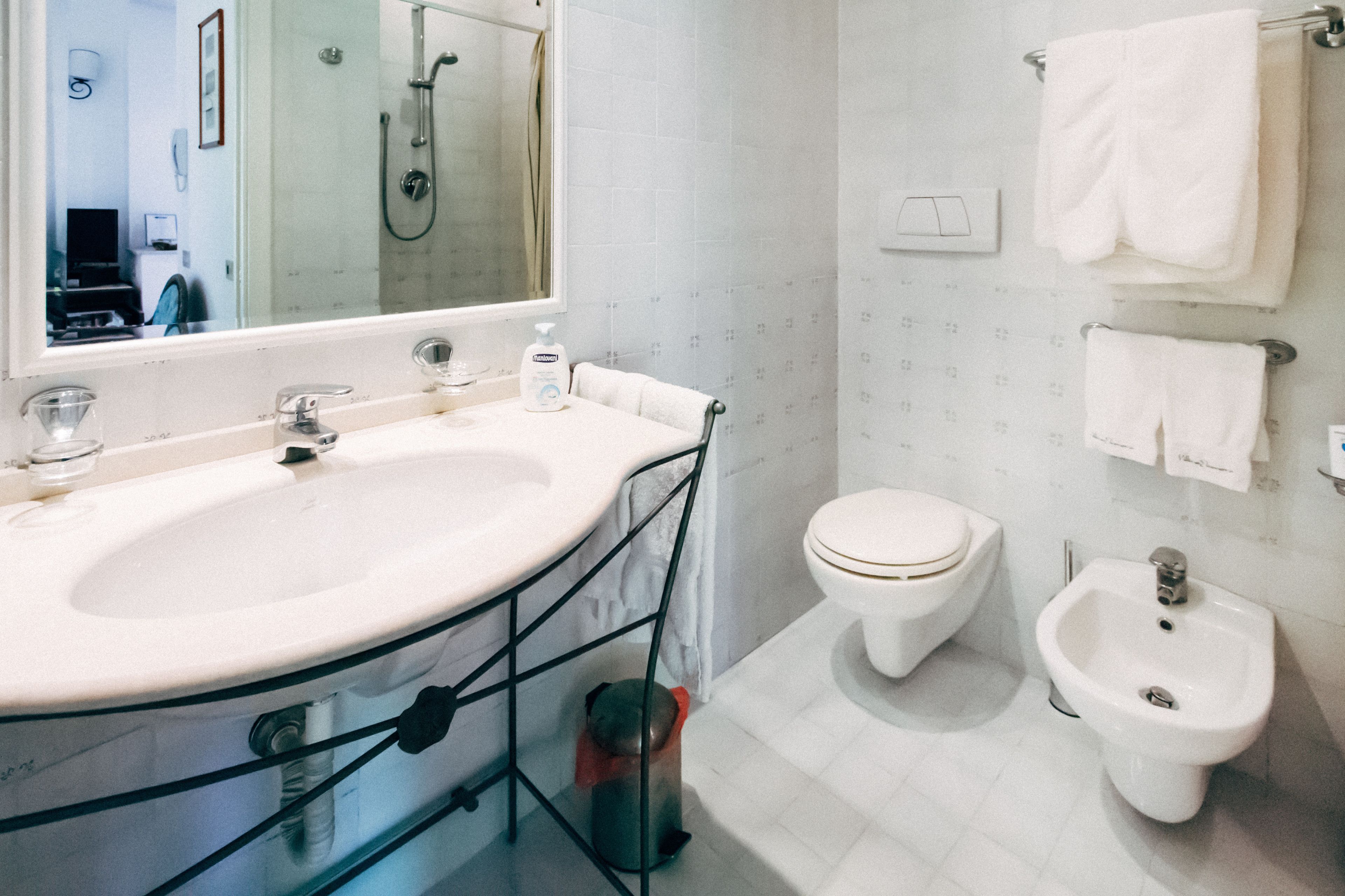 Ein modernes Badezimmer mit einem großen Waschbecken, Toilette, Bidet und einem Spiegel.