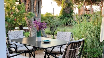 Eine Terrassengruppe mit Tisch und Stühlen, umgeben von Bäumen und Pflanzen.
