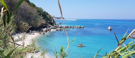 Una playa cerca, arena blanca, sombrillas, toallas de playa