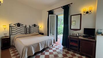 A bedroom with a checkered floor, a bed with a patterned bedspread, a nightstand, a dresser, a television, and a window with curtains.