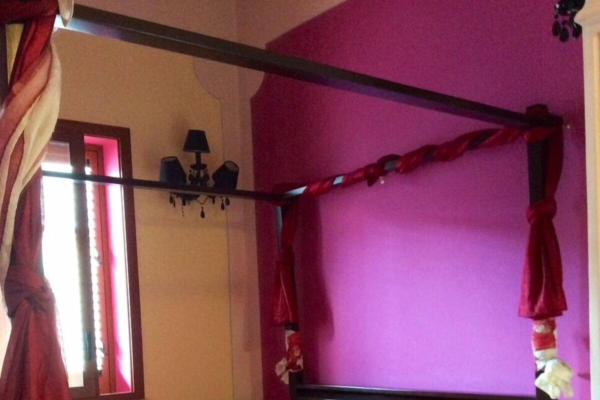 A room with a four-poster bed, a window with curtains, and a radiator.